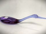 a purple spoon with a long handle sitting on a white surface