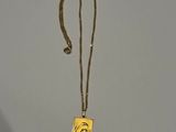 collier plaqué or avec un pendentif carré orné d'un visage