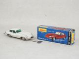une petite voiture miniature posée à côté d'une boîte sur une surface blanche