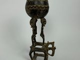 un vieux vase en bronze posé sur un socle et orné d'un oiseau