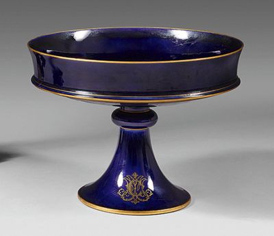 un bol bleu sur un piédestal avec une décoration en or