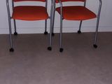 three red chairs in a room with a white wall