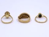 three gold rings, one with a green stone and one with a diamond