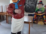 une statue représentant un chef tenant un tableau noir dans une pièce
