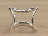 silver plated ring with a curved design on top of a wooden table