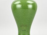 a green vase that is sitting on a white surface