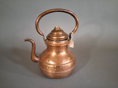 a small copper tea kettle on a gray surface