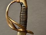 a gold colored sword with a black handle on a gray background