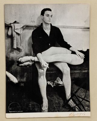 photographie en noir et blanc d'un homme assis sur un banc, les jambes croisées