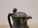 a silver tea pot with a lid on a wooden table