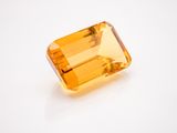 an orange sapphire stone on a white surface