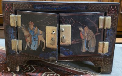 une petite armoire posée à même le sol, sur laquelle est accroché un tableau
