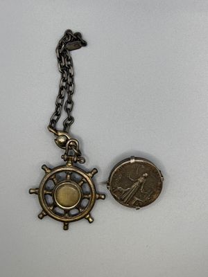 un gros plan d'une pièce de monnaie et d'un collier posés sur une surface blanche
