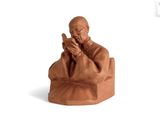 figurine of a monk sitting on a chair with his hands crossed