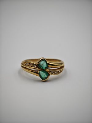gros plan d'une bague en or avec une pierre verte