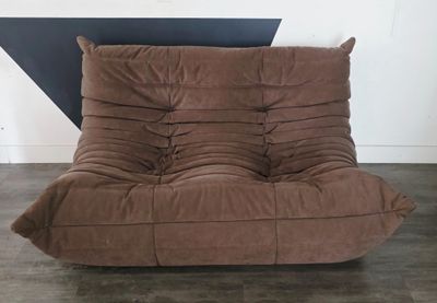 un fauteuil-futon marron dans une pièce aux murs noirs et blancs