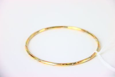 gros plan d'un bracelet en or sur une surface blanche