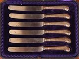 six knives in a purple case on a wooden table