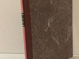 un livre à la couverture rouge posé sur une table blanche