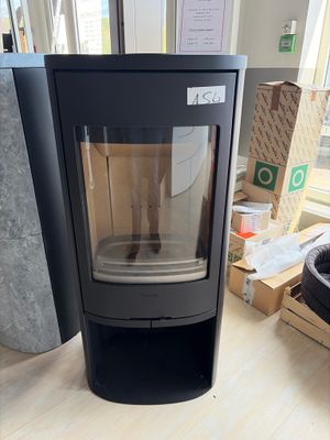 a black stove sitting on a wooden floor in front of a window