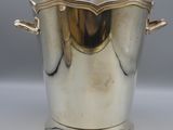 an antique silver plated ice bucket with handles on a stand