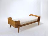 un petit lit en bois recouvert d'un drap blanc
