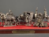 silver figurines of a horse drawn carriage with people on it