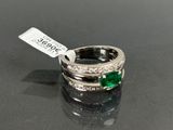 an image of a ring with emerald stones and diamonds on a black surface