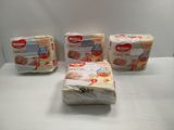 three packs of baby diapers sitting on top of a white table