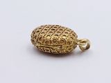 a close up of a gold plated pendant on a white surface