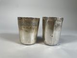 deux tasses en argent ornées de motifs sur fond blanc