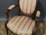 an old chair with a striped upholstered seat on a wooden floor