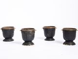 trois vases noirs munis d'anses, posés sur une surface blanche
