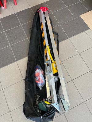 un sac noir contenant des outils, posé par terre