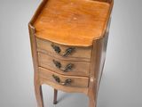 a small wooden table with three drawers on top of it