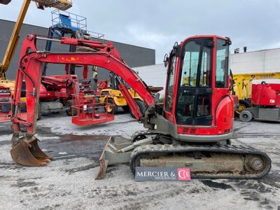 une pelleteuse rouge garée sur un parking