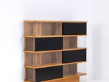 une photo d'une étagère en bois avec des tablettes noires dans une pièce blanche