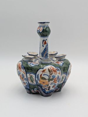 un petit vase avec un oiseau sur une surface blanche