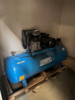 a blue air compressor sitting on a pallet in a room