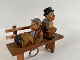 two figurines of men sitting on a wooden bench