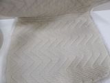 a close up of a blanket on a bed with a pillow