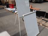 a white board sitting on the floor next to a white chair