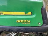 a close up of a green lawn mower parked on the side of the road