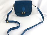 le petit sac à main bleu est posé sur une surface blanche