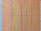 a close up of a pink and yellow rug on a bed