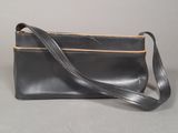 black leather purse with a strap on a grey background