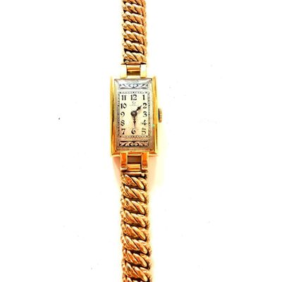une montre en or entourée d'une chaîne sur une surface blanche
