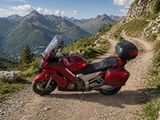 une moto rouge garée sur le bord d'un chemin de terre