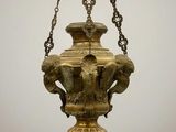 un lustre ancien en laiton suspendu à une chaîne sur un fond gris