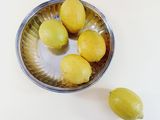 four lemons sitting in a bowl on a table